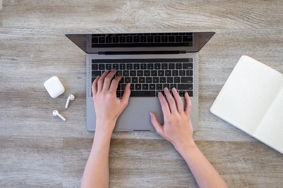Un MacBook ouvert, avec des AirPods posés à côté